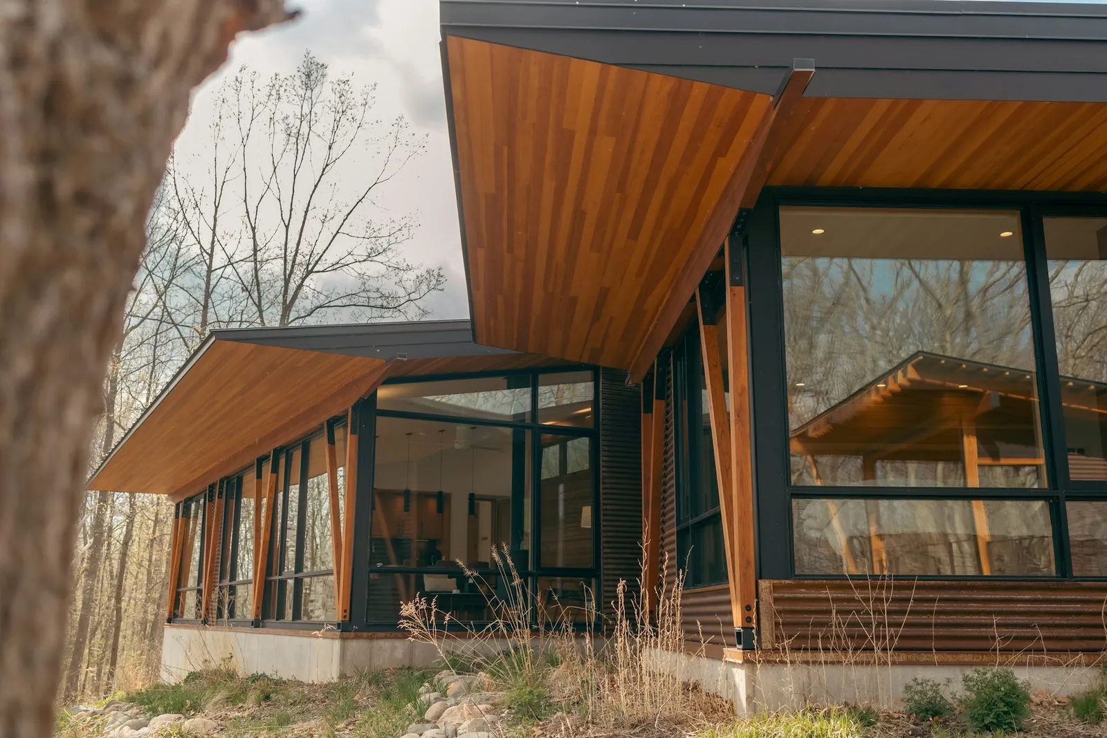 Architect-designed cottage with a wood-and-glass façade set into a wooded Quebec landscape