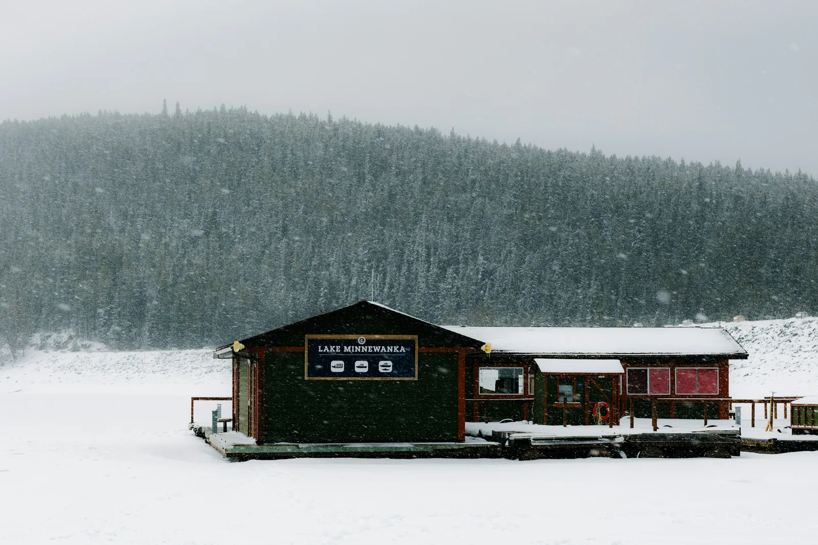 Rustic cottage on the shore of a frozen lake under snow, winter in a resort region