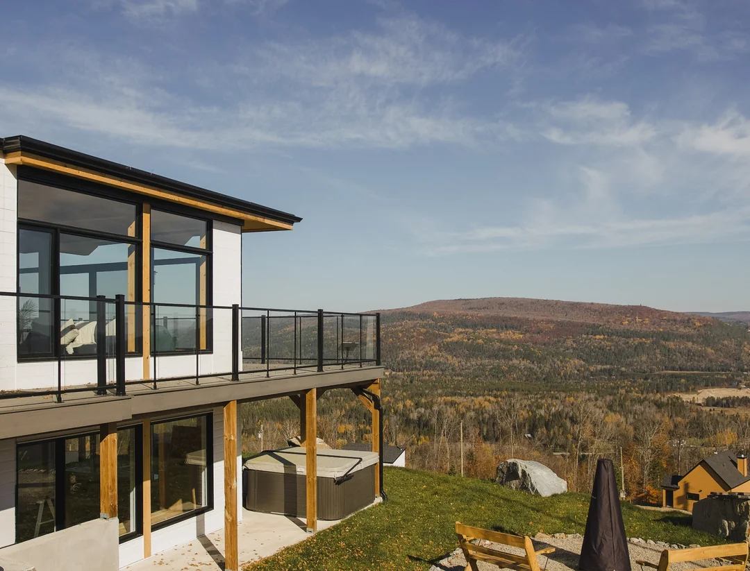 View of a cottage near Val Saint-Côme with a balcony, hot tub and mountain panorama in autumn