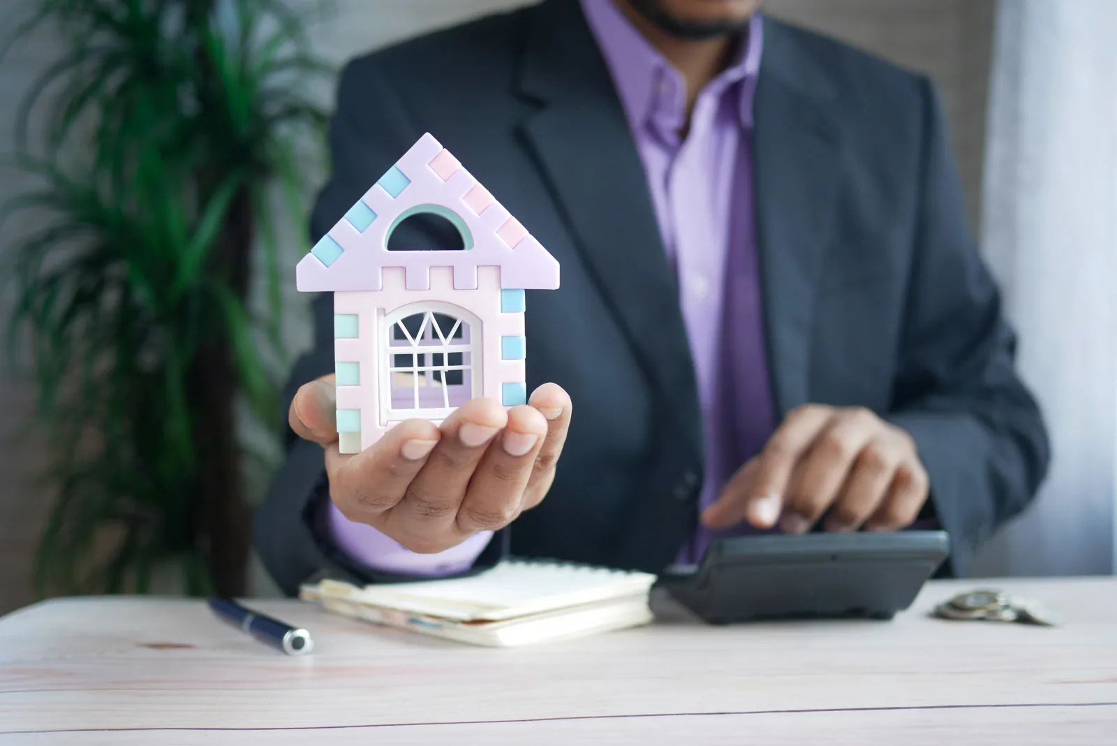Person in a suit holding a miniature house and a calculator, illustrating rental cottage financing