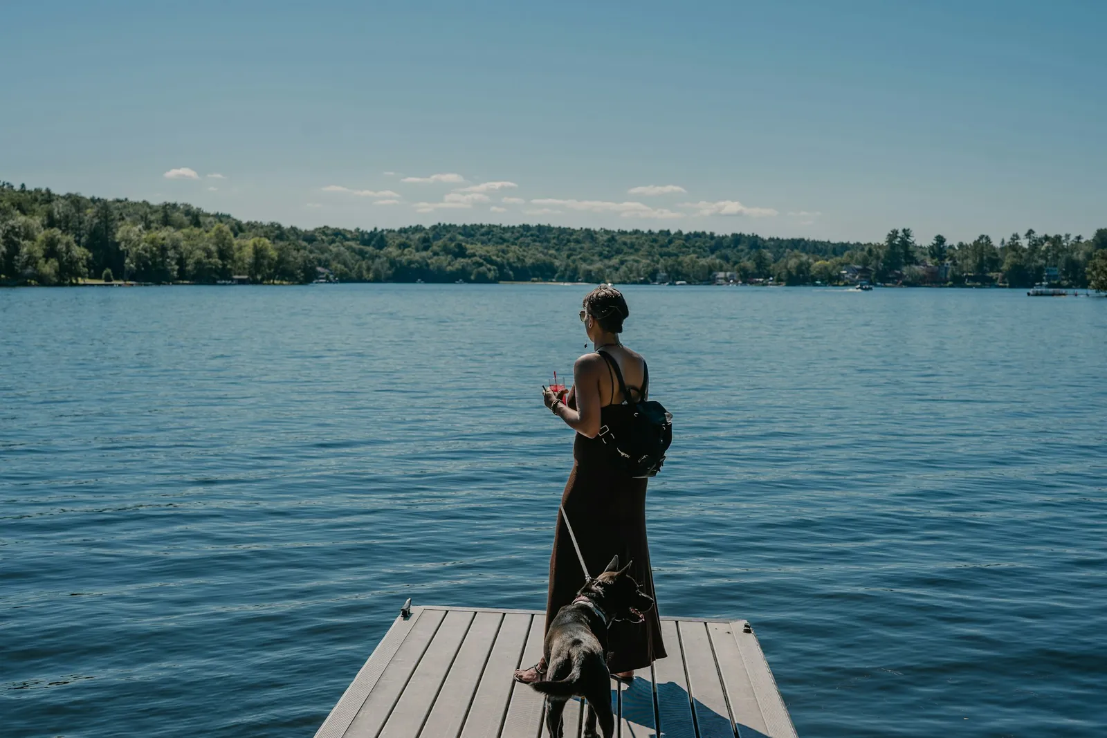 Propriétaire de chalet et son chien sur un quai en bord de lac par une journée d'été au Québec