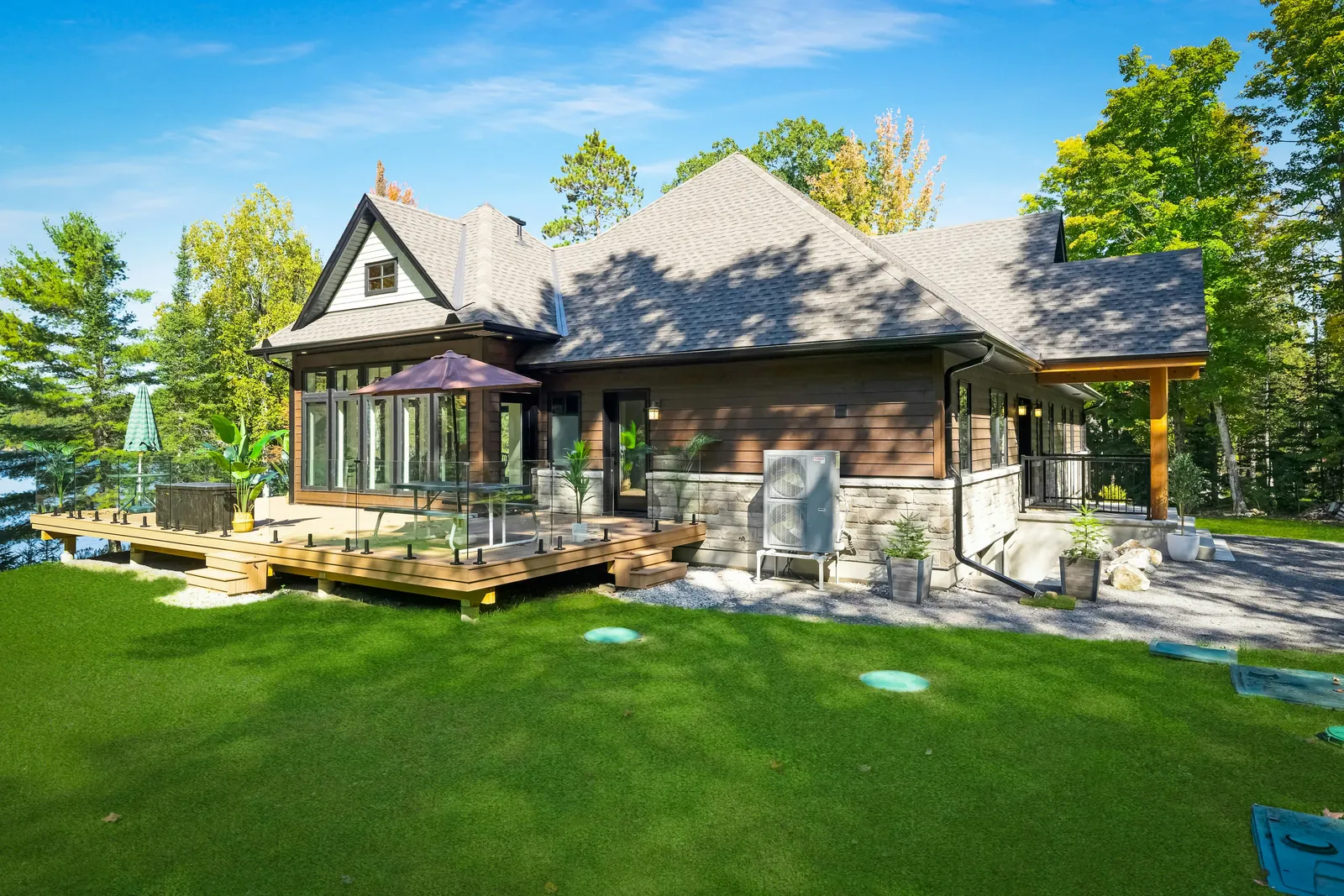 Prestige waterfront property with a wooden deck and glass railing overlooking a lake